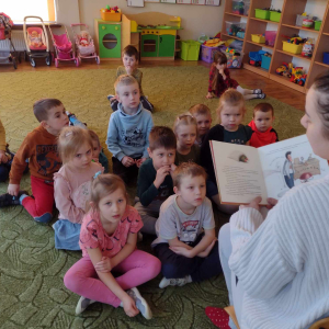 Dzieci słuchają bajki czytanej przez rodzica.