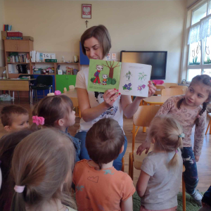 Dzieci oglądają kolorowe obrazki w książce.