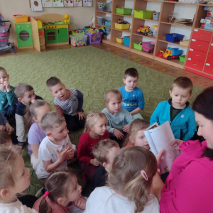 Dzieci słuchają bajki czytanej przez rodzica.