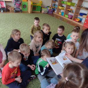 Dzieci słuchają bajki czytanej przez rodzica.