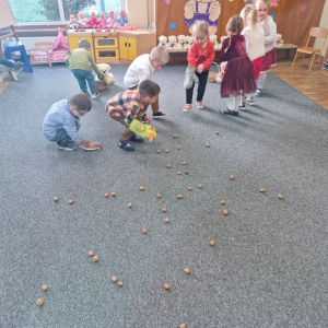 Dzieci zbierają orzechy kuchenną rękawicą założoną na rękę     
