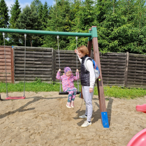 Mama huśta córkę na huśtawce