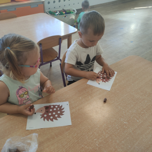 Dzieci wyklejają szablon jeża plasteliną