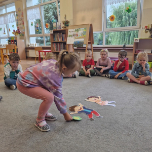 Dziewczynka kładzie kwiatek przy obrazkach dzieci