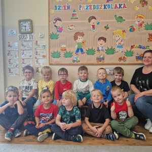 Chłopcy z Panią Wioletą na tle dekoracji  Dzień Przedszkola