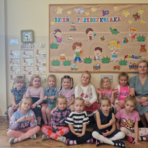 Dziewczynki z Panią Marysią na tle dekoracji Dzień Przedszkolaka