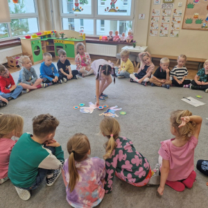 Dziewczynka kładzie kwiatek przy obrazkach dzieci