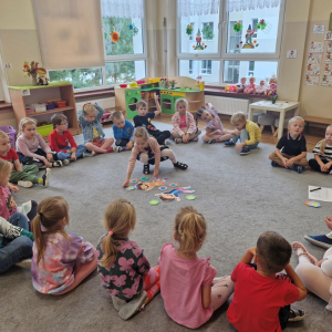 Dziewczynka kładzie kwiatek przy obrazkach dzieci