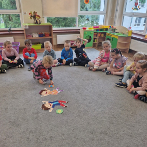 Dziewczynka kładzie kwiatek przy obrazkach dzieci