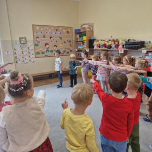 Dzieci wskazują na chłopca  - maszynistę prowadzącego "pociąg"