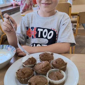 chłopiec, który polewa babeczki polewą