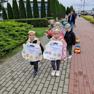 Dzieci w czasie przemarszu na stadion ciągną na sznurku samochody