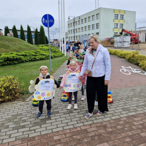 Dzieci w czasie przemarszu na stadion ciągną za sobą samochody  na sznurku samochody