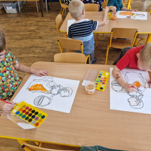 Chłopcy w czasie malowania  obrazka Pani Jesieni farbami akwarelowymi