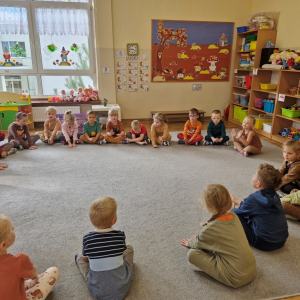 Dzieci rytmicznie uderzają dłońmi  o podłogę śpiewając refren piosenki