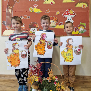 Chłopcy z obrazkami Pani Jesieni na tle dekoracji jesiennej