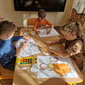 Dzieci w czasie malowania farbami akwarelowymi obrazka Pani Jesieni