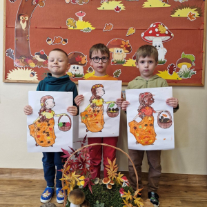 Chłopcy z obrazkami Pani Jesieni na tle dekoracji jesiennej
