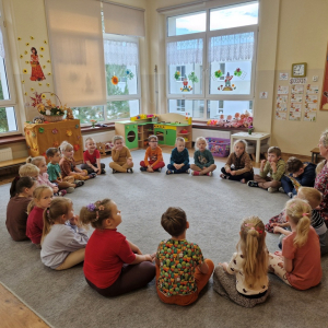 Dzieci siedząc  w kole, słuchają piosenki o jesieni