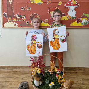 Dzieci z obrazkami Pani Jesieni na tle dekoracji jesiennej