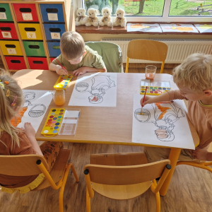 Chłopcy w czasie malowania  obrazka Pani Jesieni farbami akwarelowymi