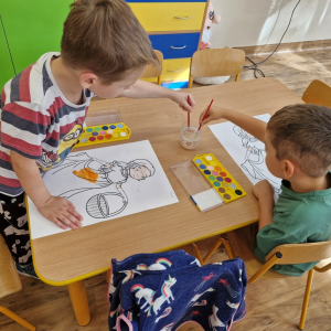 Chłopcy w czasie malowania  obrazka Pani Jesieni farbami akwarelowymi