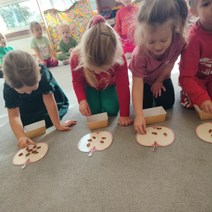 Dzieci układające pestki na jabłku.