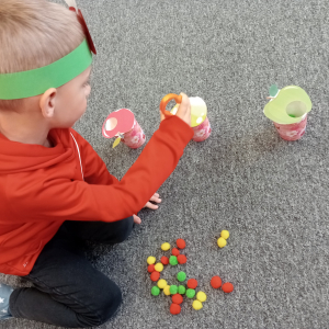 chłopiec segregujący pomponiki do odpowiedniego jabłuszka