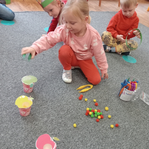 dziewczynka segregująca pomponiki do odpowiedniego jabłuszka