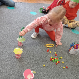 dziewczynka segregująca pomponiki do odpowiedniego jabłuszka