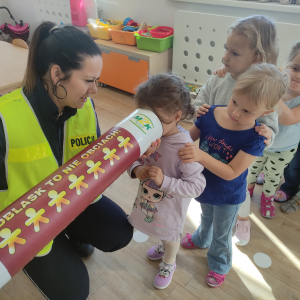 Pani policjantka pokazująca tubę z odblaskami