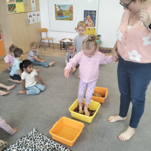 Dziewczynka chodząca po ścieżce sensorycznej z liści, kasztanów i wody