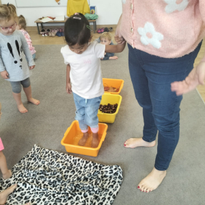 Dziewczynka chodząca po ścieżce sensorycznej z liści, kasztanów i wody