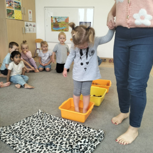 Dziewczynka chodząca po ścieżce sensorycznej z liści, kasztanów i wody