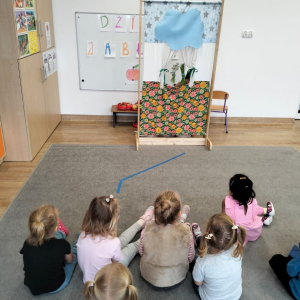 Dzieci oglądające teatrzyk kukiełkowy pod tytułem "Na straganie"