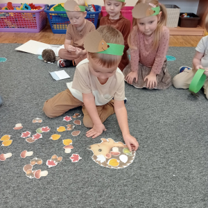 chłopiec dopasowuje obrazki do odpowiedniego konturu