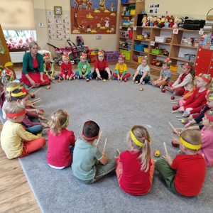 Dzieci stukają pałeczkami o podłogę w rytm śpiewanej    piosenki