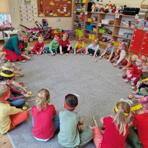 Dzieci podczas śpiewu piosenki rysują jabłka na dywanie