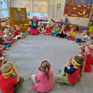 Dzieci trzymają w rękach jabłko, śpiewając piosenkę