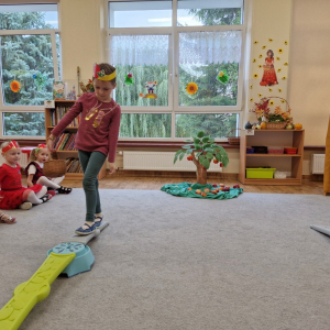 Dziewczynka idzie po dróżce, trzymając koszyk z jabłek