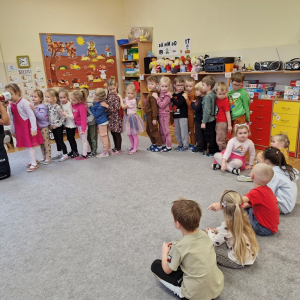 Dziewczynka patrzy  w tubę, aby zobaczyć   jak  wygląda w ciemności   człowiek w kamizelce  odblaskowej lub bez niej