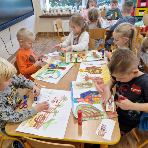 Dzieci wycinają lub naklejają obrazki "Jasia", "Małgosi" lub "chatkę Baby Jagi" na wcześniej namalowany las 