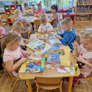 Dzieci wycinają lub naklejają obrazki "Jasia", "Małgosi" lub "chatkę Baby Jagi" na wcześniej namalowany las 