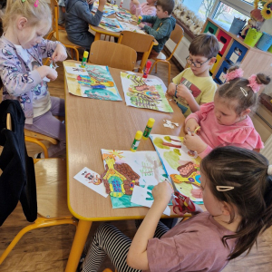 Dzieci wycinają lub naklejają obrazki "Jasia", "Małgosi" lub "chatkę Baby Jagi" na wcześniej namalowany las 