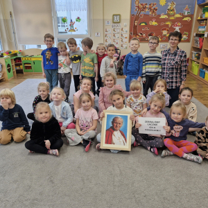Dzieci z Panią Gabrysią (nauczycielką religii) trzymają obraz Jana Pawła II i kartkę z informacją o zebranej kwocie pieniężnej na Fundację Dzieło Nowego Dziesięciolecia