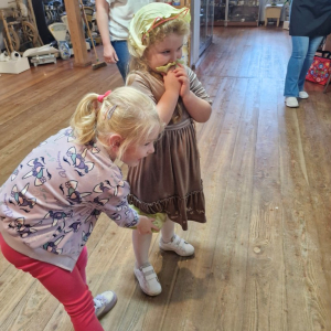 Dziewczynka pomaga trzymać listek kapusty przyłożony do kolana koleżanki