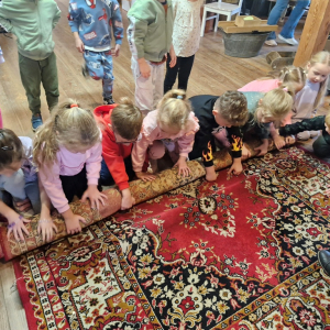 Dzieci zwijają dywan w rulon