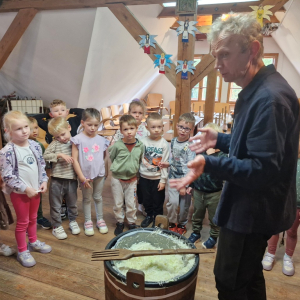 Dzieci oglądają pokrojoną kapustę i wielki widelec służący do wymieszania kapusty z solą i marchwią