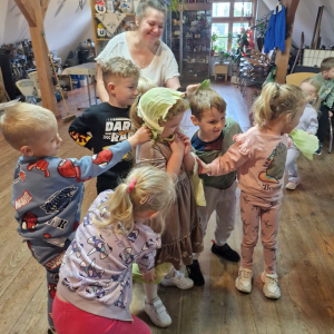 Dzieci pomagają trzymać listki kapusty przyłożone do różnych części ciała koleżanki