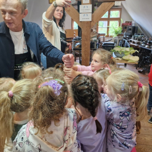 Dzieci z pomocą pana Krzysztofa ubijają kapustę w beczce